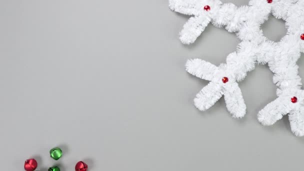 毛茸茸的白色雪花圣诞装饰与移动的银铃灰色背景 新年和圣诞节假期的概念 恭喜你 复制空间 从上面看 — 图库视频影像