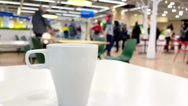 ショッピングモールの人々の明るい背景を持つテーブル上のホワイトコーヒーカップ 高品質の4K映像 — ストック動画