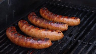 Izgara barbekü sosisleri paslanmaz ızgarada ve alevler yakın. Yiyecek ve mutfak konsepti