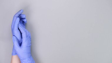 Doktorun ya da hemşirenin mavi eldivenleriyle fotokopi çekilen gri arka plan üzerinde. Tıbbi eldivenler