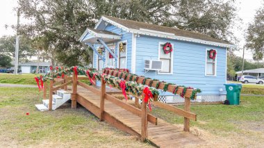 Charming Small Blue Cottage with Festive Christmas Decorations and Palm Trees in the Yard - Kenly, NC USA 03.15.2024. clipart