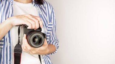 Elinde DSR kamerası olan bir fotoğrafçı. Otoportre, ön manzara. Yüzsüz, kızıl saçlı, tişörtlü, elinde fotoğraf makinesi olan hoş bir kadın. Beyaz arka plan.