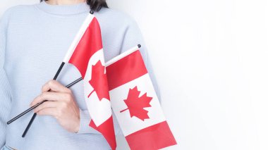 Gri arka planda küçük Kanada bayrağı taşıyan beyaz tişörtlü tanınmamış kız çocuğu, Kanada günü, tatil, oy, göç, vergi, kopya alanı.