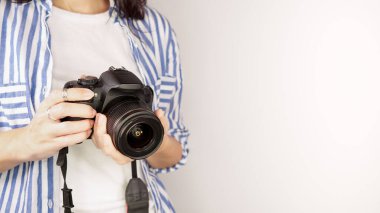 Elinde DSR kamerası olan bir fotoğrafçı. Otoportre, ön manzara. Yüzsüz, kızıl saçlı, tişörtlü, elinde fotoğraf makinesi olan hoş bir kadın. Beyaz arka plan.