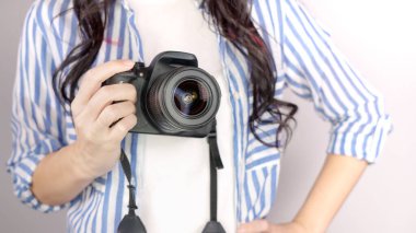 Elinde DSR kamerası olan bir fotoğrafçı. Otoportre, ön manzara. Yüzsüz, kızıl saçlı, tişörtlü, elinde fotoğraf makinesi olan hoş bir kadın. Beyaz arka plan.