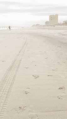 Açık kahverengi kumdaki geniş lastik izinin detaylı bir görüntüsü, muhtemelen ağır bir araçtan. Koyu kahverengi iz, yaklaşık 12 inç genişliğinde, insan etkisinin doğal manzaralar üzerinde olduğunu gösteriyor..