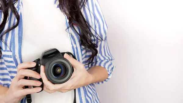 Elinde DSR kamerası olan bir fotoğrafçı. Otoportre, ön manzara. Yüzsüz, kızıl saçlı, tişörtlü, elinde fotoğraf makinesi olan hoş bir kadın. Beyaz arka plan.