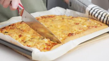Kadının pizzayı bıçakla kestiği videoyu kapat. Ev yapımı pizza. Taze pişmiş vejetaryen pizza.