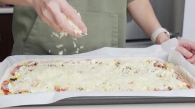 Izgara peynir, aşçının elinden pizzanın üzerine düşer. Ev yapımı pizza. Pizza için rendelenmiş peynir.