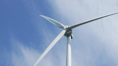Gezegen 'in iyiliği için dönen ve yeşil ekolojik enerji üreten mavi gökyüzüne karşı bir rüzgar türbininin görüntüsünü kapat. Yel değirmeni Temiz Yenilenebilir Enerji Üretiyor