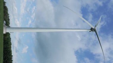 Gezegenin iyiliği için dönen ve yeşil ekolojik enerji üreten mavi gökyüzüne karşı tam ölçekli bir rüzgâr türbini çekimi. Windmill Temiz Yenilenebilir Enerji Üretiyor. Dikey video