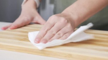 Eller tahta kesme tahtasını kağıt havluyla siliyor. Mutfakta Kadın Tezgahı Temizliyor, Yemek Hazırlıyor