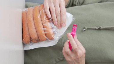 Eller depolamak için sosis torbasını şarjörle kapatıyor. Uzun vadeli depolama paketinde et sosisi
