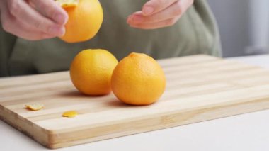 Masadaki kesme tahtasının üzerinde portakal kabuğu soyulmuş eller, Noel 'de yemek yapmak için bir sürü sulu taze meyve..