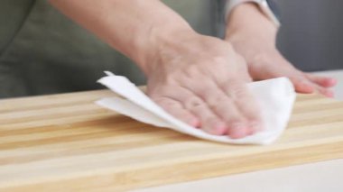 Eller tahta kesme tahtasını kağıt havluyla siliyor. Mutfakta Kadın Tezgahı Temizliyor, Yemek Hazırlıyor