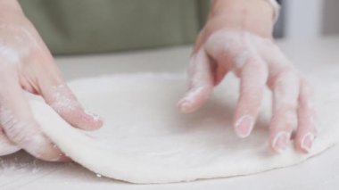 Pizza hazırlama - kadınların elleri un kaplı bir masada hamur yoğurur. Ev yapımı pizza.