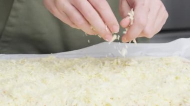 Izgara peynir, aşçının elinden pizzanın üzerine düşer. Ev yapımı pizza. Pizza için rendelenmiş peynir.