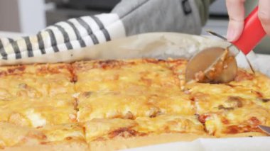 Yuvarlak bir bıçakla pizza kesmek. Lezzetli pizzanın parçalara ayrıldığı yakın plan çekimler. Yavaş çekimde bir pizzayı kesiciyle birden fazla dilime ayırmak.