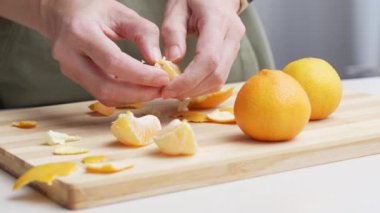 Masadaki kesme tahtasının üzerinde portakal kabuğu soyulmuş eller, Noel 'de yemek yapmak için bir sürü sulu taze meyve..