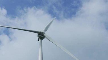 Gezegen 'in iyiliği için dönen ve yeşil ekolojik enerji üreten mavi gökyüzüne karşı bir rüzgar türbininin görüntüsünü kapat. Yel değirmeni Temiz Yenilenebilir Enerji Üretiyor