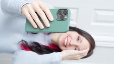 Telefona odaklan. Kameraya konuşan mutlu genç kız elinde bir telefon kayıt videosu tutuyor. Sarışın kadın nüfuzlu sosyal medya yayını, evdeki akıllı telefonu kullanarak online sohbet videosu.