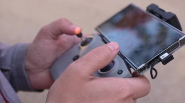 Bir Drone operatörünün eli doğada bir kuadkopter uzaktan kumandası kullanırken yakınlaşır. Modern teknoloji kavramı akıllı dijital kablosuz cihaz. Helikopter kamerasıyla kadın video kaydı.