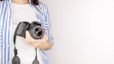 Elinde DSR kamerası olan bir fotoğrafçı. Otoportre, ön manzara. Yüzsüz, kızıl saçlı, tişörtlü, elinde fotoğraf makinesi olan hoş bir kadın. Beyaz arka plan.