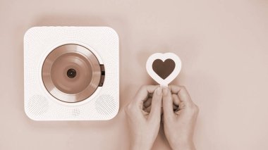 Ellerinde beyaz CD çalar ve kahverengi arka planda kalp şeklinde hediye kartı var. Yılın Rengi Mocha Mousse. Aşk müziği, Sevgililer Günü, Selamlama