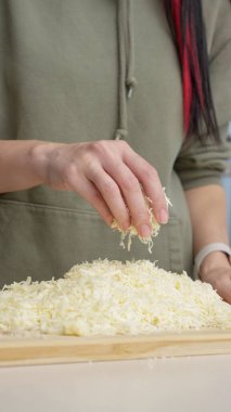 Izgara peynir aşçının elinden düşer. Pizza için rendelenmiş peynir.