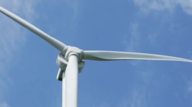 Gezegen 'in iyiliği için dönen ve yeşil ekolojik enerji üreten mavi gökyüzüne karşı bir rüzgar türbininin görüntüsünü kapat. Yel değirmeni Temiz Yenilenebilir Enerji Üretiyor