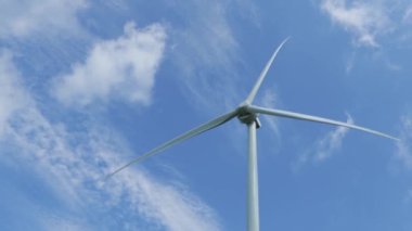 Gezegen 'in iyiliği için dönen ve yeşil ekolojik enerji üreten mavi gökyüzüne karşı bir rüzgar türbininin görüntüsünü kapat. Yel değirmeni Temiz Yenilenebilir Enerji Üretiyor