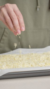 Izgara peynir, aşçının elinden pizzanın üzerine düşer. Ev yapımı pizza. Pizza için rendelenmiş peynir.