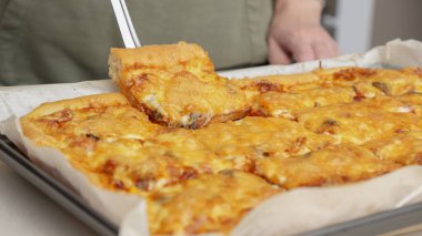 Tahta masa üzerinde servis edilen peynirli ve sosisli ev yapımı kare pizza tam peynirli organik pizza sağlıklı pizza..