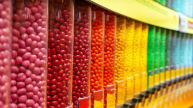 Temiz plastik kaplarda sergilenen renkli yuvarlak şekerler, düzenli bir sırada dizilmiş. Şekerleme endüstrisiyle ilgili geçmiş ve çizimler için mükemmel..
