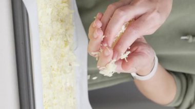 Izgara peynir, aşçının elinden pizzanın üzerine düşer. Ev yapımı pizza. Pizza için rendelenmiş peynir.