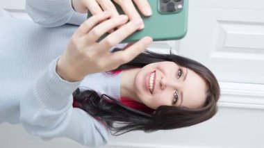 Kameraya konuşan mutlu genç kız elinde bir telefon kayıt videosu tutuyor. Sarışın kadın nüfuzlu sosyal medya yayını, evdeki akıllı telefonu kullanarak online sohbet videosu.