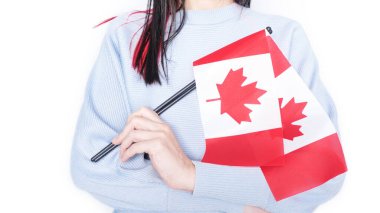 Mavi gömlekli tanınmamış bir kız çocuğu gri arka planda küçük Kanada bayrağı taşıyor, Kanada günü, tatil, oy, göçmenlik, vergi, kopya alanı.