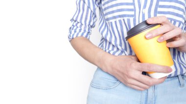 Karnının önünde siyah kapaklı sarı bir kahve fincanı tutan bir kadın..