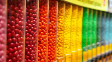 Temiz plastik kaplarda sergilenen renkli yuvarlak şekerler, düzenli bir sırada dizilmiş. Şekerleme endüstrisiyle ilgili geçmiş ve çizimler için mükemmel..
