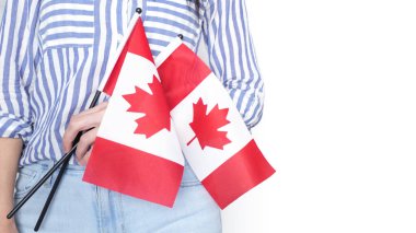 Gri arka planda küçük Kanada bayrağı taşıyan beyaz tişörtlü tanınmamış kız çocuğu, Kanada günü, tatil, oy, göç, vergi, kopya alanı.