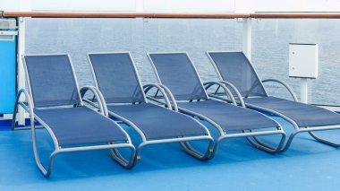 Lüks bir yolcu gemisinin güvertesinde düzgün sıralarda dizilmiş mavi güverte koltuklarının huzurlu manzarası.