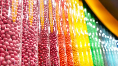 Temiz plastik kaplarda sergilenen renkli yuvarlak şekerler, düzenli bir sırada dizilmiş. Şekerleme endüstrisiyle ilgili geçmiş ve çizimler için mükemmel..