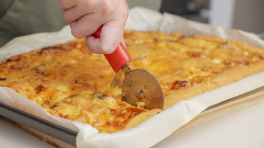 Yuvarlak bir bıçakla pizza kesmek. Lezzetli pizzanın parçalara ayrıldığı yakın plan çekimler. Yavaş çekimde bir pizzayı kesiciyle birden fazla dilime ayırmak.