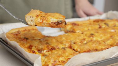 Tahta masa üzerinde servis edilen peynirli ve sosisli ev yapımı kare pizza tam peynirli organik pizza sağlıklı pizza..