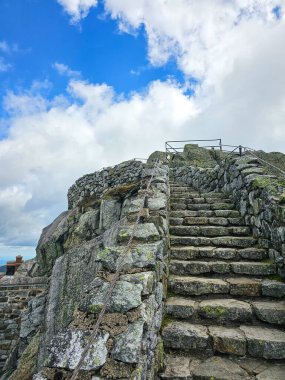 Taştan bir merdiven bir dağa çıkıyor ve doğanın güzelliğini keşfetmeye davet ediyor. Mavi gökyüzü ve bulutlar atmosferik bir zemin oluşturuyor. Bu da onu macera için ideal bir stok sahnesi yapıyor..
