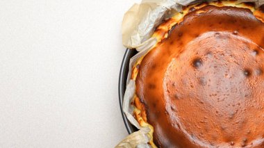 Beyaz arka planda çatlakları olan ev yapımı lezzetli fırınlanmış cheesecake 'in göz kamaştırıcı üst görüntüsü.