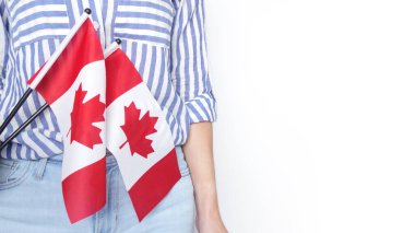 Gri arka planda küçük Kanada bayrağı taşıyan beyaz tişörtlü tanınmamış kız çocuğu, Kanada günü, tatil, oy, göç, vergi, kopya alanı.