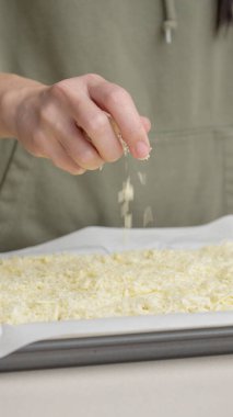 Izgara peynir, aşçının elinden pizzanın üzerine düşer. Ev yapımı pizza. Pizza için rendelenmiş peynir.
