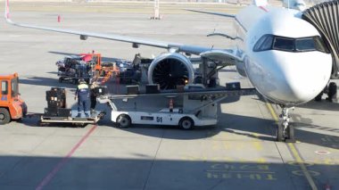 Bişkek, Kırgızistan - 10.09.2024: Havaalanında bir uçak hizmet veriyor. Yer mürettebatı bavul ve kargoyu uçağa yüklüyor. Olay yeri yoğun bir havaalanı ortamı gösteriyor..