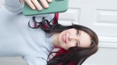 Kameraya konuşan mutlu genç kız elinde bir telefon kayıt videosu tutuyor. Sarışın kadın nüfuzlu sosyal medya yayını, evdeki akıllı telefonu kullanarak online sohbet videosu.